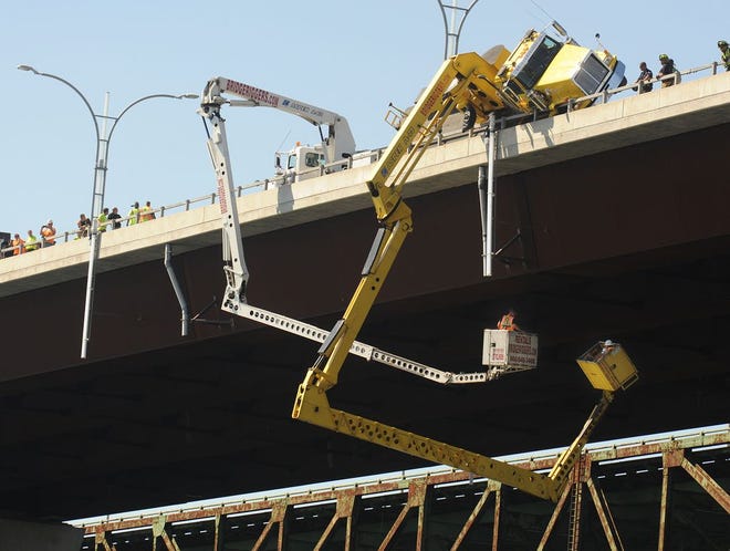 Two men are retrieved from beneath the Sakonnet River Bridge after their bridge inspection unit's truck, on the northbound lane of Route 24, tipped onto the rail, trapping them suspended over the water in August. After suspending the use of those trucks, they are once again in use.
