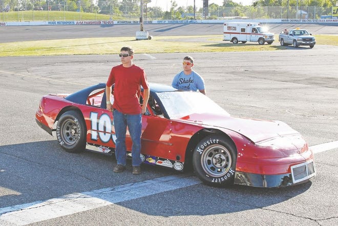 Collin (left) and his twin brother Caleb stand on the track with their grandfather’s car. (Photo courtesy of RAND THOMPSON/Flat Rock Speedway)