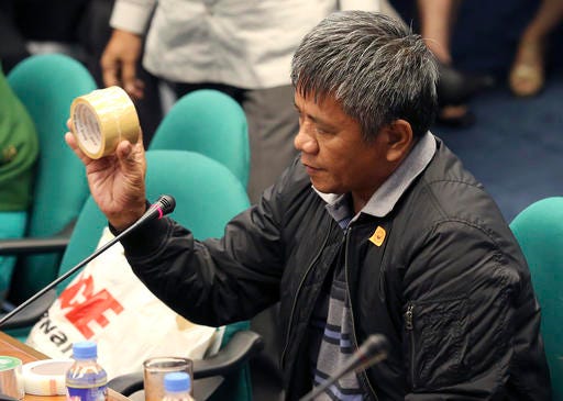 Former Filipino militiaman Edgar Matobato shows the kind of tape they use to wrap up dead bodies as he testifies before the Philippine Senate in Pasay, south of Manila, Philippines on Thursday Sept. 15, 2016. Matobato said that Philippine President Rodrigo Duterte, when he was still a city mayor, ordered him and other members of a squad to kill criminals and opponents in gangland-style assaults that left about 1,000 dead. (AP Photo/Aaron Favila)