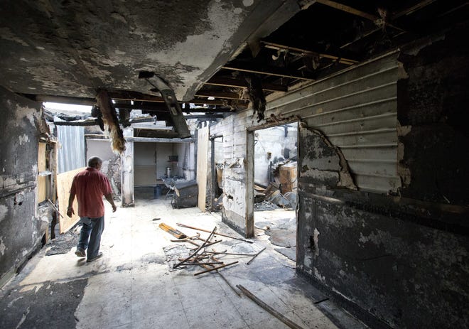 Farhad Khan, left, who has attended the Islamic Center of Fort Pierce for more than seven years, walks through its charred remains on Thursday in Fort Pierc. An ex-convict who posted anti-Islamic rants online confessed to setting fire to the mosque that the Orlando nightclub shooter occasionally attended, and said he was embarrassed by the crime, according to an arrest affidavit released Thursday. AP PHOTO / WILFREDO LEE