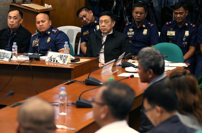Philippine Police Chief Ronald Dela Rosa, second from left, looks at former Filipino militiaman Edgar Matobato during his testimony at the Philippine Senate in Pasay, south of Manila, Philippines on Thursday, Sept. 15, 2016. Matobato said that Philippine President Rodrigo Duterte, when he was still a city mayor, ordered him and other members of a squad to kill criminals and opponents in gangland-style assaults that left about 1,000 dead. (AP Photo/Aaron Favila)