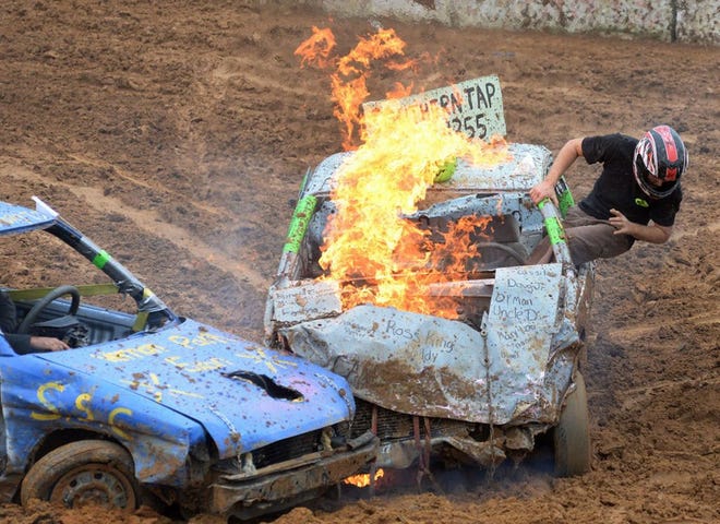 A driver jumps from the window after his car caught fire at the Lenoir County Fair’s popular demolition derby on Sept. 26, 2015.