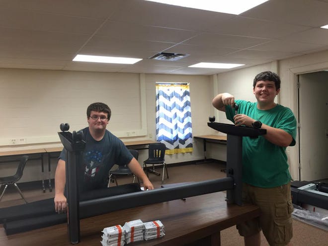 Hunter King and Gavin Smith, students in Mulberry High School's EAST Initiative, assemble the plotter stand for the plotter printer in the new EAST Initiative room. SUBMITTED PHOTO