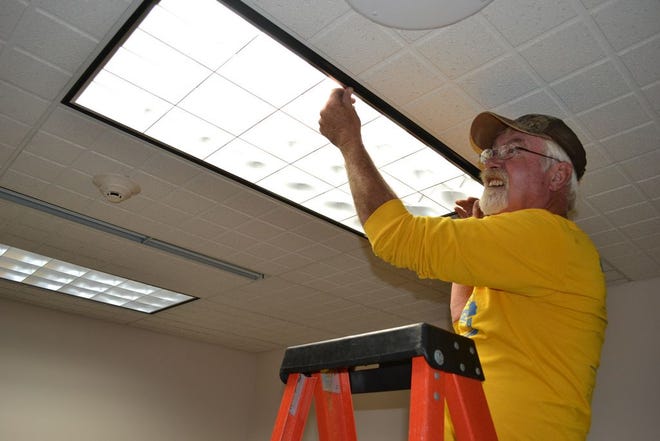 John Lenz, Perry city employee, finishes installing more LED lights in a Perry Public Library study room Friday.