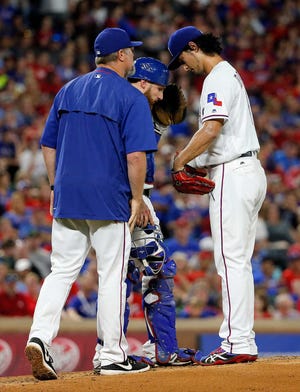 Texas pitching coach Doug Brocail, left, and catcher Jonathan Lucroy, center, visit starting pitcher Yu Darvish on the mound on Saturday in Arlington. Darvish gave up seven runs in an 11-2 loss to the A's.