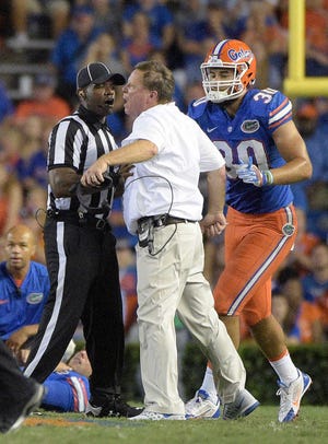 Florida coach Jim McElwain is restrained by an official and tight end DeAndre Goolsby (30) after quarterback Luke Del Rio was knocked out of the game during the second half of an NCAA college football game against North Texas in Gainesville, Fla., Saturday, Sept. 17, 2016. North Texas was penalized for roughing the passer. (AP Photo/Phelan M. Ebenhack)