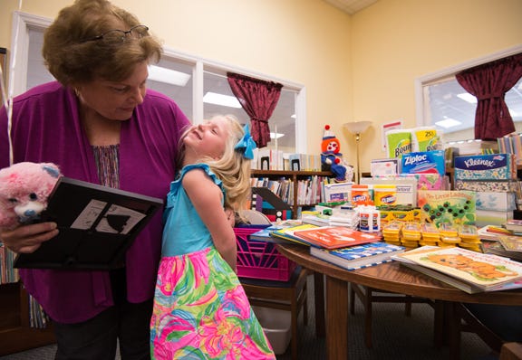 Jewel Smith, left, an assistant librarian in charge of children's programming at the Cove City Library, presents Olivia Sanderling a certificate after she donated items to the Cove City Library in lieu of birthday presents.