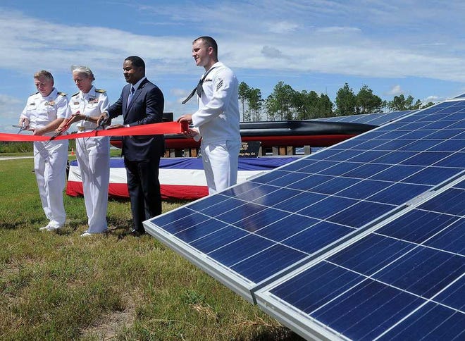 Kings Bay commanding officer, Capt. James Jenks, from left, Rear Adm. Mary M. Jackson, commander of U.S. Navy Region Southeast, Georgia Power Senior Vice President of Marketing Kenneth E. Coleman, watch the ribbon they'd just cut Monday flutter to the ground at the new $75 million solar power farm on Kings Bay Naval Submarine Base.