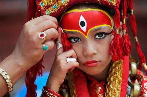 In this Wednesday, Sept. 14, 2016 file photo, a Nepalese mother applies make up to her daughter dressed as the living goddess Kumari as they wait for Kumari puja to start at Hanuman Dhoka temple in Kathmandu, Nepal. Girls under the age of nine gathered for the Kumari puja, a tradition of worshiping young prepubescent girls as manifestations of the divine female energy. The ritual holds a strong religious significance in the Newar community that seeks divine blessings to save small girls from diseases and bad luck in the years to come. (AP Photo/Niranjan Shrestha, File)