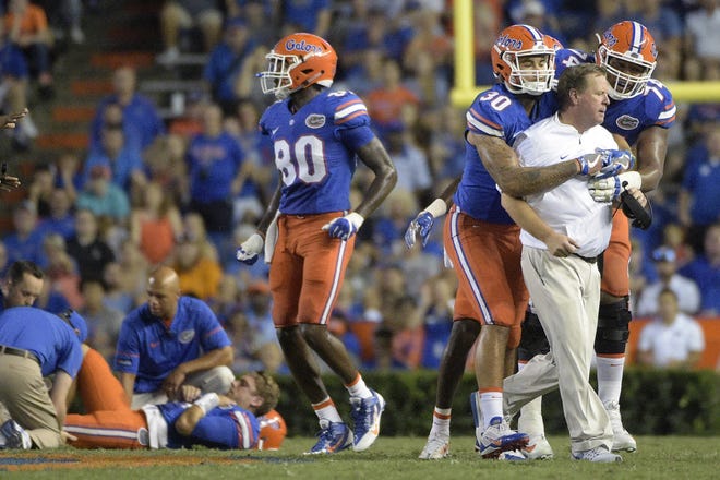 Florida coach Jim McElwain is restrained by tight end DeAndre Goolsby and offensive lineman Fred Johnson after McElwain showed his displeasure after quarterback Luke Del Rio, left, was knocked out of the game during the second half of a college football game against North Texas in Gainesville., Saturday, Sept. 17, 2016. North Texas was penalized for roughing the passer. THE ASSOCIATEGD PRESS / PHELAN M. EBENHACK