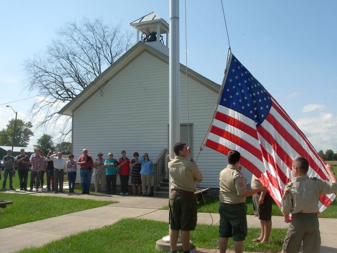 Members of Boy Scout Troop 508 raise the flag at the restored one-room McGowan Schoolhouse in Exeter Township. (Monroe News photo by DEAN COUSINO)