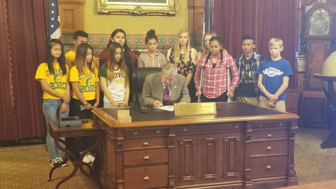 Jaqueline Guardado, a Perry High School freshman, stands to the right of Gov. Terry Branstad Monday as the governor signs a proclamation declaring Sept. 19 through 23 GEAR UP Week in Iowa. SUBMITTED PHOTO