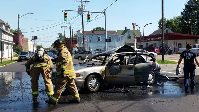 Firefighters Wednesday inspect a vehicle that burst into flames after it was rear-ended by another vehicle which fled the scene at Ninth Street and Deuber Avenue SW in Canton, a fire official said.