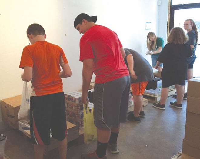 Members of the First Baptist Church youth group make packs for the Backpack program. Courtesy photo