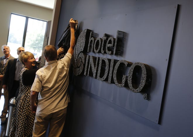 Steve Davis, the artist who created the sign, and Amy Echols, director of Kentuck Art Center, unveil the lobby sign in Hotel Indigo during the opening of the new facility Wednesday. Davis created the sign using more than 300 nails. Staff Photo/Gary Cosby Jr.