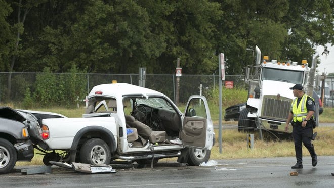 An Austin police officer looks at the scene of a fatal crash on U.S 183 at Burleson Road on Thursday August 20, 2015. Two people died in the crash.
