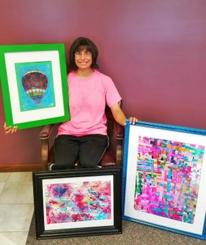 Andi Bolton, who is enrolled in art classes at the Memorial Behavioral Health-Lincoln Center for Developmental Rehabilitation, shows off some of the artwork that will be on display at an opening reception on Oct. 6 at the Lincoln Art Institute. Up to 60 artists will display their work at the month-long exhibit. Photo submitted