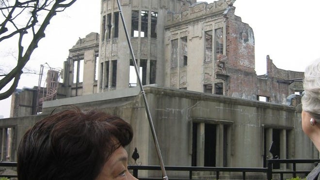 A tourist guide walks past the Atomic Bomb Dome, which is near where the atomic bomb hit. Photo by Si Liberman