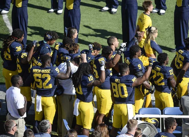 Michigan football players raise their fists up in protest during the National Anthem, before an NCAA college football game against Penn State, Saturday, Sept. 24, 2016, in Ann Arbor, Mich. (Junfu Han/The Ann Arbor News via AP)