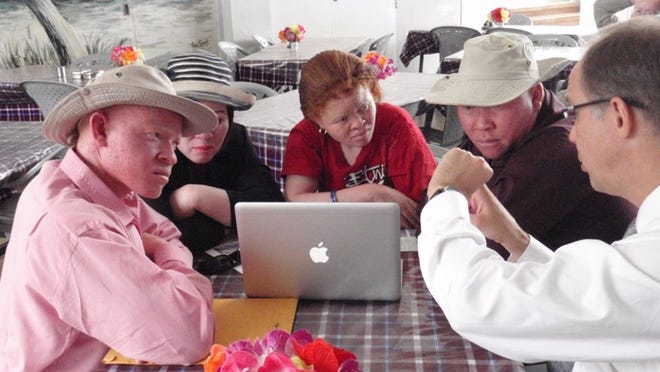 Strasswimmer, of Palm Beach, educates people with albinism about ways to prevent skin cancer. He is shown during a 2013 trip to Tanzania talking to members of that country’s Albino Association.