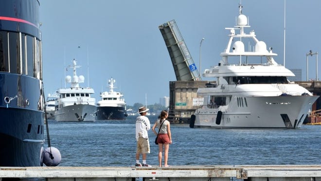 Mike Krupa with his daughter, Mariel, from Athens, Ga., watch large yachts preparing to dock Tuesday for the 30th annual Palm Beach International Boat Show.
