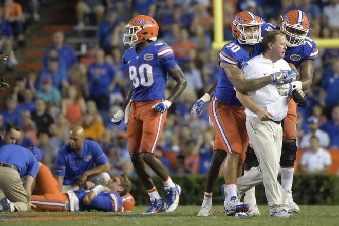 Florida coach Jim McElwain is restrained by tight end DeAndre Goolsby (30) and offensive lineman Fred Johnson (74) after McElwain showed his displeasure after quarterback Luke Del Rio, left, was knocked out of the game during the second half of a college football game against North Texas in Gainesville, Saturday, Sept. 17, 2016. North Texas was penalized for roughing the passer. THE ASSOCIATED PRESS / PHELAN M. EBENHACK