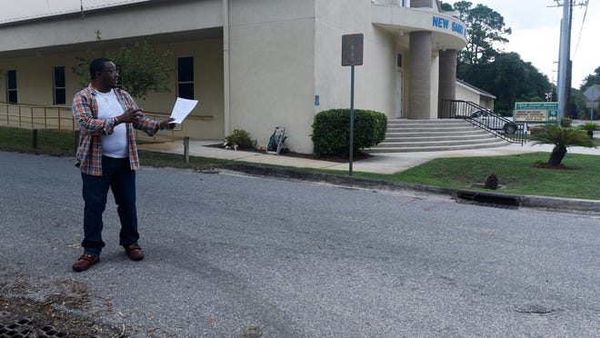 christina.kelso@staugustine.com — Norsalus Jackson, director of operations for the New St. James Missionary Baptist Church, stands on a downsloping stretch of Cathedral Place adjacent to the West Augustine church on Wednesday September 28, 2016. With the printout of the county ordinance requiring facilities to maintain their drainage systems in his hand, Jackson demonstrates how stormwater flows down the street and into the county’s drains on each side. These drains then cut into the church’s private drainage system, overwhelming it and causing water to flow across the intersection of North Rodriguez Street, damaging the church’s parking lot.