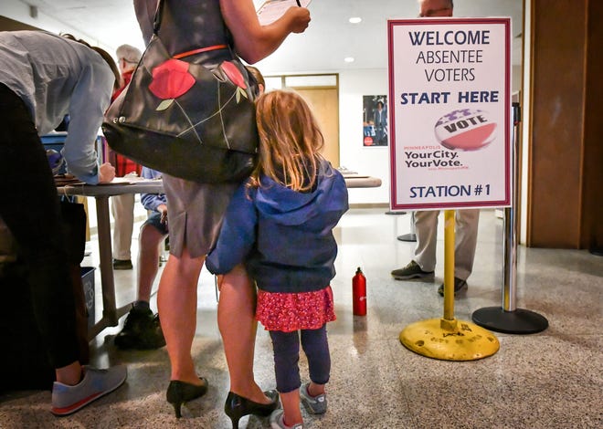Isabel Bender holds on to her mom while accompanying her to a voting center in Minneapolis recently. Absentee voting in Florida starts Tuesday. Glen Stubbe/Star Tribune via AP