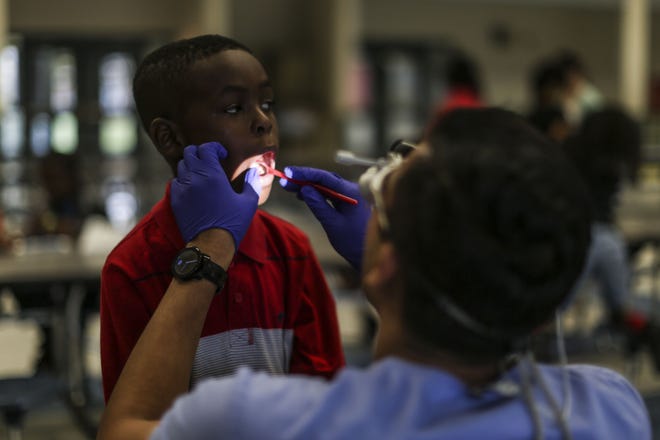 Rick Patel, a 25-year-old UF dental student, gives Jo'Marion Welch, 8, a dental screening at Lake Forest Elementary School in Gainesville, Fla., Sept. 29, 2016. Health screenings are often the best way to detect problems that interfere with students´ education. Andrea Cornejo/ Correspondent