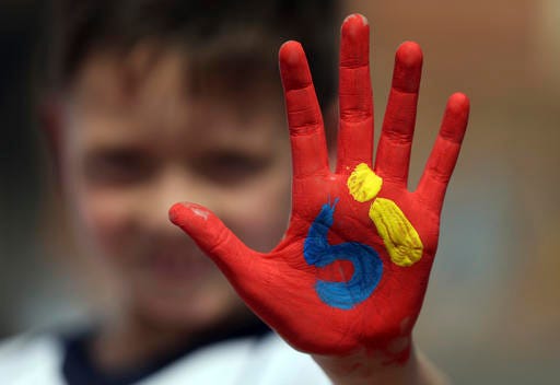 A boy shows his hand painted with the word "Yes" in Spanish during an event attended by Colombia's President Juan Manuel Santos to promote the "yes" vote in the upcoming referendum on the peace deal he signed with rebels Revolutionary Armed Forces of Colombia, FARC, in Soacha, in the outskirts of Bogota, Colombia, Friday, Sept. 30, 2016. Colombians go to the polls on Oct. 2 in a referendum where they will be asked to ratify or reject the accord. (AP Photo/Fernando Vergara)