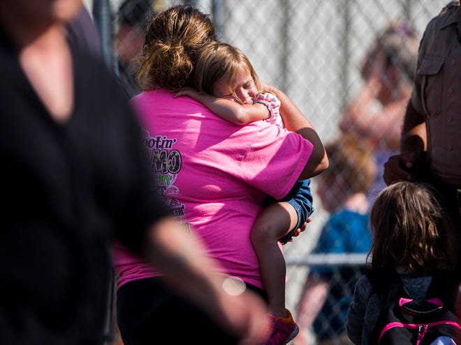 A child holds onto a caretaker after being picked up by her at Oakdale Baptist Church, following a shooting at Townville Elementary in Townville Wednesday, Sept. 28, 2016. A teenager killed his father at his home Wednesday before going to the nearby elementary school and opening fire with a handgun, wounding two students and a teacher, authorities said. (Katie McLean/The Independent-Mail via AP)