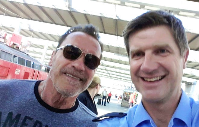 In this Oct.1, 2016 photo provided by the Munich police former Californian state governor Arnold Schwarzenegger poses with police officer Stefan Schmitt for a selfie in the main train station in Munich, Germany. Schwarzenegger's bodyguard was stopped when cycling with Schwarzenegger too fast through the train station. As an apologize Schwarzenegger offered a selfie. (Stefan Schmitt/Munich police via AP)
