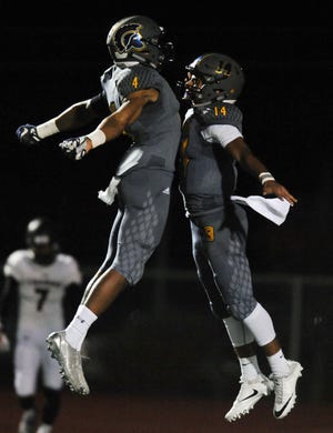 Battle’s Jaevon McQuitty, left, and Brevinn Tyler celebrate a touchdown during Friday night’s 44-36 overtime victory against Truman. After their homecoming game, the Spartans had a moment of silence for assistant Jon Dinter.