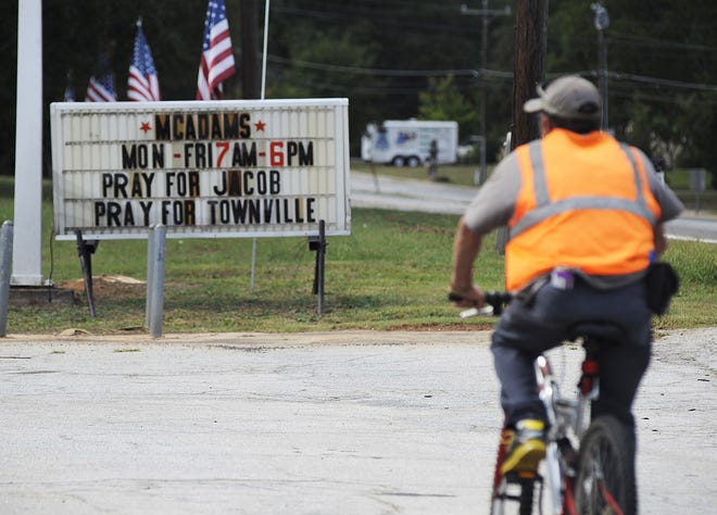 A bicyclist rides past a sign urging prayer for victims of a school shooting in Townville, S.C., on Thursday, Sept. 29, 2016. Authorities say two students and a teacher were wounded by a gunman at an elementary school. (AP Photo/Jay Reeves)