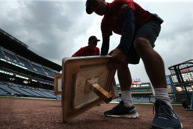 ADVANCE FOR SATURDAY, OCT. 1 - In this Sept. 27, 2016, file photo, the grounds crew prepares the bases at Turner Field as the Atlanta Braves prepare to play the Philadelphia Phillies in a baseball game in Atlanta. Turner Field began its brief life as the main stadium for the 1996 Summer Olympics. After just two decades as the home of the Atlanta Braves, it's headed for another transformation. The Braves are moving to the suburbs next season, leaving the Ted to Georgia State University. (Curtis Compton/Atlanta Journal-Constitution via AP, File