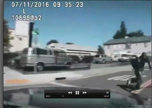 A image from video from a dash-mounted camera in a Sacramento Police Department vehicle, shows Joseph Mann, right, run past moments before he is shot and killed by officers, July 11, 2016 in Sacramento, Calif. The Mann family is demanding that the officers involved in the shooting of Joseph Mann, 50, be charged with murder and that the U.S. Department of Justice open a civil rights investigation of the police department. (Sacramento Police Department via AP)