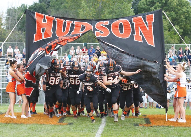 The Hudson football team busts through a sign before a game this season.