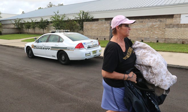 Sue Bathrick of Port Orange carries bedding and supplies into Sweetwater Elementary School in Port Orange, which was one of many evacuation sites in the area Thursday morning. News-Journal/JIM TILLER
