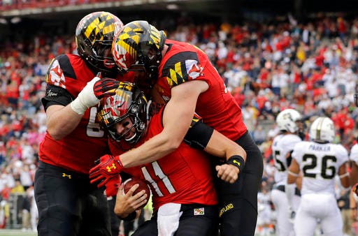FILE - In this Saturday, Oct. 1, 2016, file photo, Maryland quarterback Perry Hills (11) celebrates his touchdown with teammates Mike Minter, left, and Avery Edwards in the first half of an NCAA college football game against Purdue in College Park, Md. Coming off a season in which he threw 13 interceptions, Hills has done a masterful job of running unbeaten Maryland's high-powered offense. (AP Photo/Patrick Semansky, File)