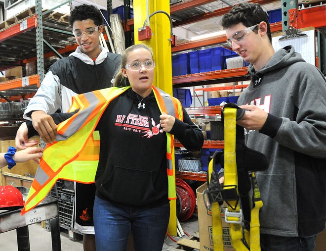 Lauren Klein, a senior at Hatboro-Horsham High School, gets help putting on safety equipment from fellow students Clifton Moore and Alex Singer during a group visit to Worth & Co., of Pipersville on Friday, Oct. 7, 2016.