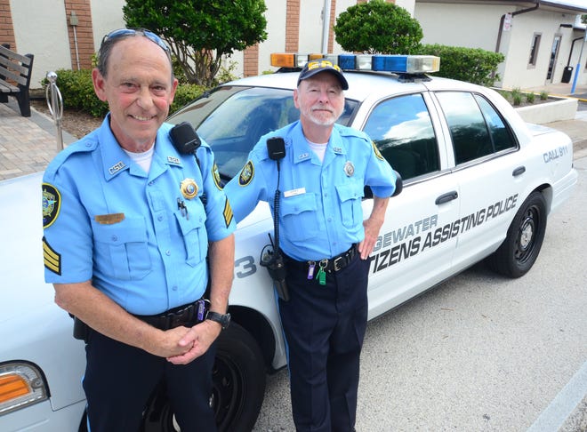 Sgt. David Soltz, left, and volunteer Jerry Cain stand along side one of four Edgewater Citizens Assisting Police patorl cars. News-Journal/Kelly Faulkenham
