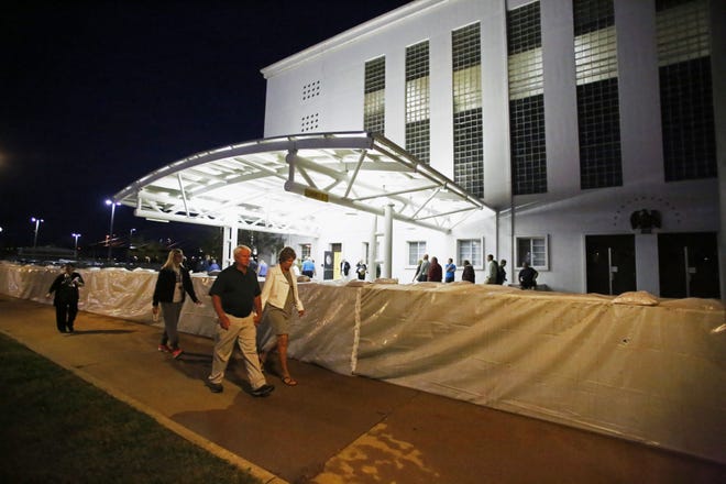 Theater attendees walk around a flood barrier to enter Memorial Auditorium to see Capitol Steps Thursday in Burlington.