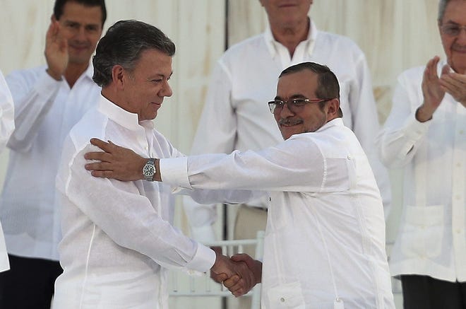 FILE - In this Monday, Sept. 26, 2016 file photo, ColombiaþÄôs President Juan Manuel Santos, left, and the top commander of the Revolutionary Armed Forces of Colombia (FARC) Rodrigo Londono, known by the alias Timochenko, shake hands after signing a peace agreement between ColombiaþÄôs government and the FARC to end over 50 years of conflict in Cartagena, Colombia. Santos won the Nobel Peace Prize Friday, Oct. 7, for his efforts to end a civil war that killed more than 200,000 Colombians. (AP Photo/Fernando Vergara, File)