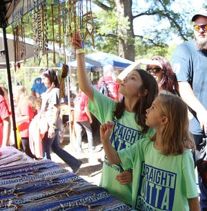 Kaedynce Peel, 8, reaches up at an arrowhead necklace as she and Ranae Holcomb, 8, look at jewelry during their third grade class field trip from Hamilton Elementary to the Native American Festival held at Moundville Archeological Park on Thursday, Oct. 6.  Staff Photo/Erin Nelson