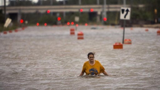 A woman who identified herself as Valerie walks along flooded President Street after leaving her homeless camp after Hurricane Matthew caused flooding, Saturday, Oct. 8, 2016, in Savannah, Georgia. Matthew plowed north along the Atlantic coast, flooding towns and gouging out roads in its path. (AP Photo/Stephen B. Morton)