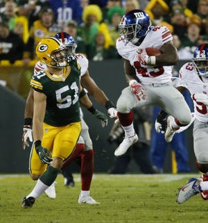New York Giants' Bobby Rainey runs past Green Bay Packers' Kyler Fackrell (51) during the second half Sunday. ASSOCIATED PRESS / MIKE ROEMER