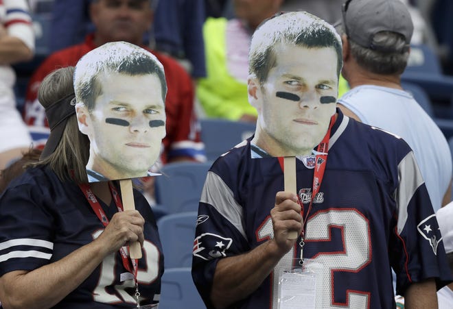 New England Patriots fans hold up masks of quarterback Tom Brady before an NFL football game between the Patriots and the Miami Dolphins. Brady returns to the field today. AP PHOTO BY CHARLES KRUPA