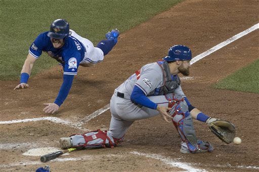 Toronto’s Josh Donaldson, left, scores as Texas catcher Jonathan Lucroy tries to catch the ball after the Rangers failed to turn a double play. Donaldson’s score gave the Blue Jays a 7-6 10-inning victory in Game 3 of the AL Division Series.