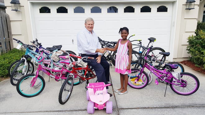Ken Hair receives a $300 donation of bikes for the children living at the Children in Crisis Neighborhood from 9-year-old Marlee Green. SPECIAL TO THE LOG