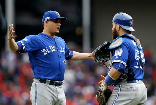 Toronto Blue Jays' Roberto Osuna, left, and catcher Russell Martin, right, celebrate their 5-3 win against the Texas Rangers after the final out of Game 2 of baseball's American League Division Series, Friday, Oct. 7, 2016, in Arlington, Texas. (AP Photo/LM Otero)